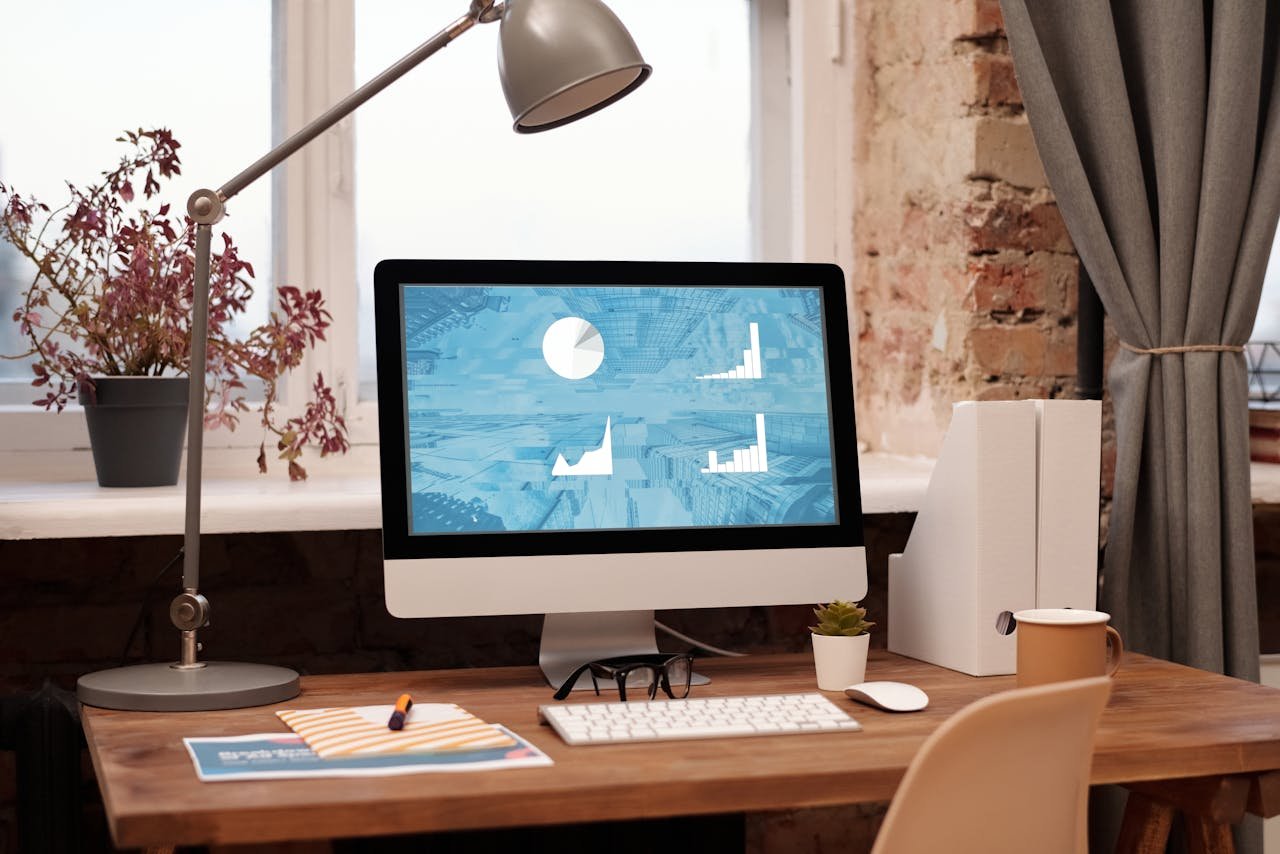 Clean and modern home office setup with computer, lamp, and decor. Ideal for productivity in a contemporary workspace.